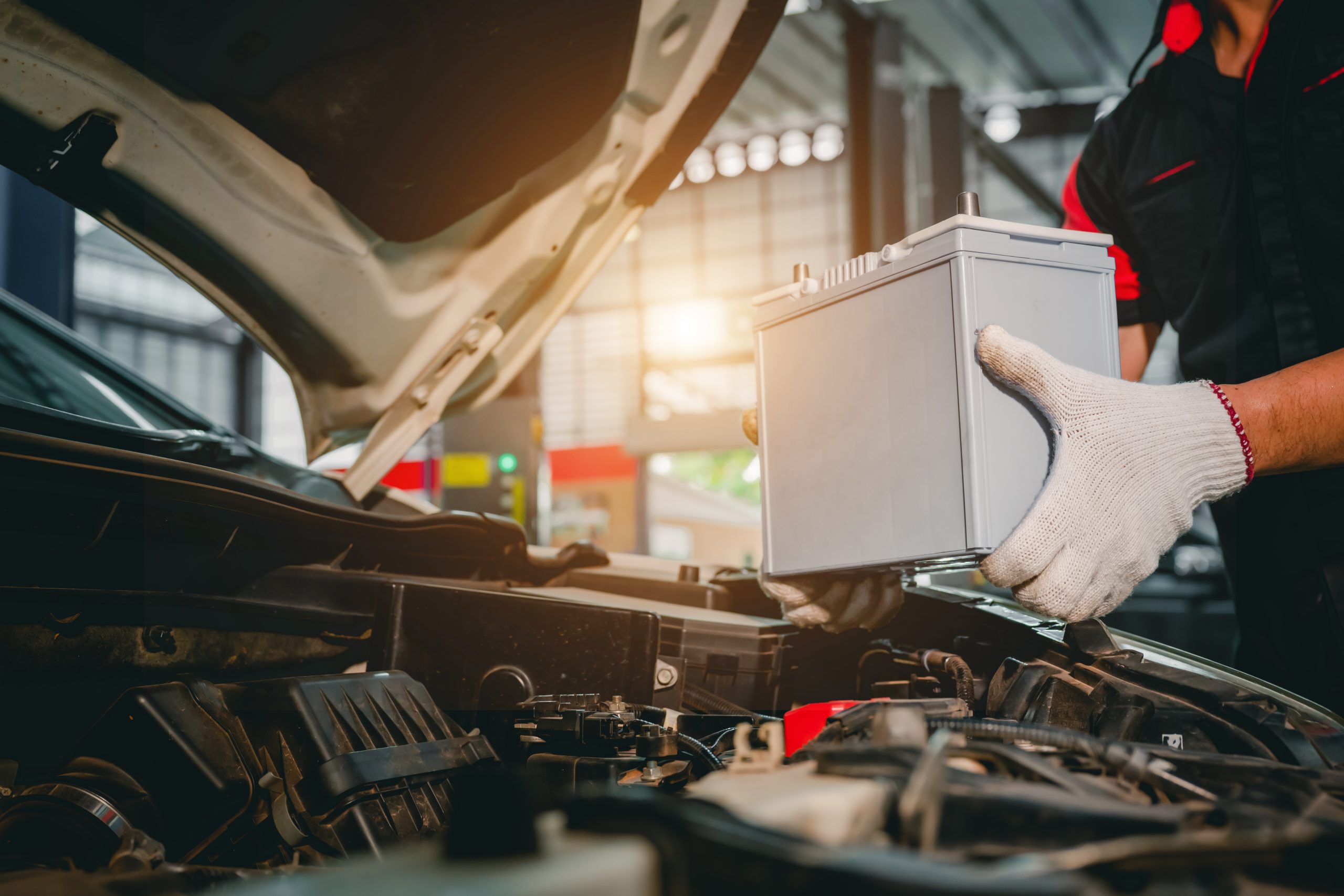 A car mechanic in a service center picking up a new battery to replace the car. for cars that use the service Replace the battery at the store Trusted Car Battery Replacement Katy, TX | Northwest Express Auto