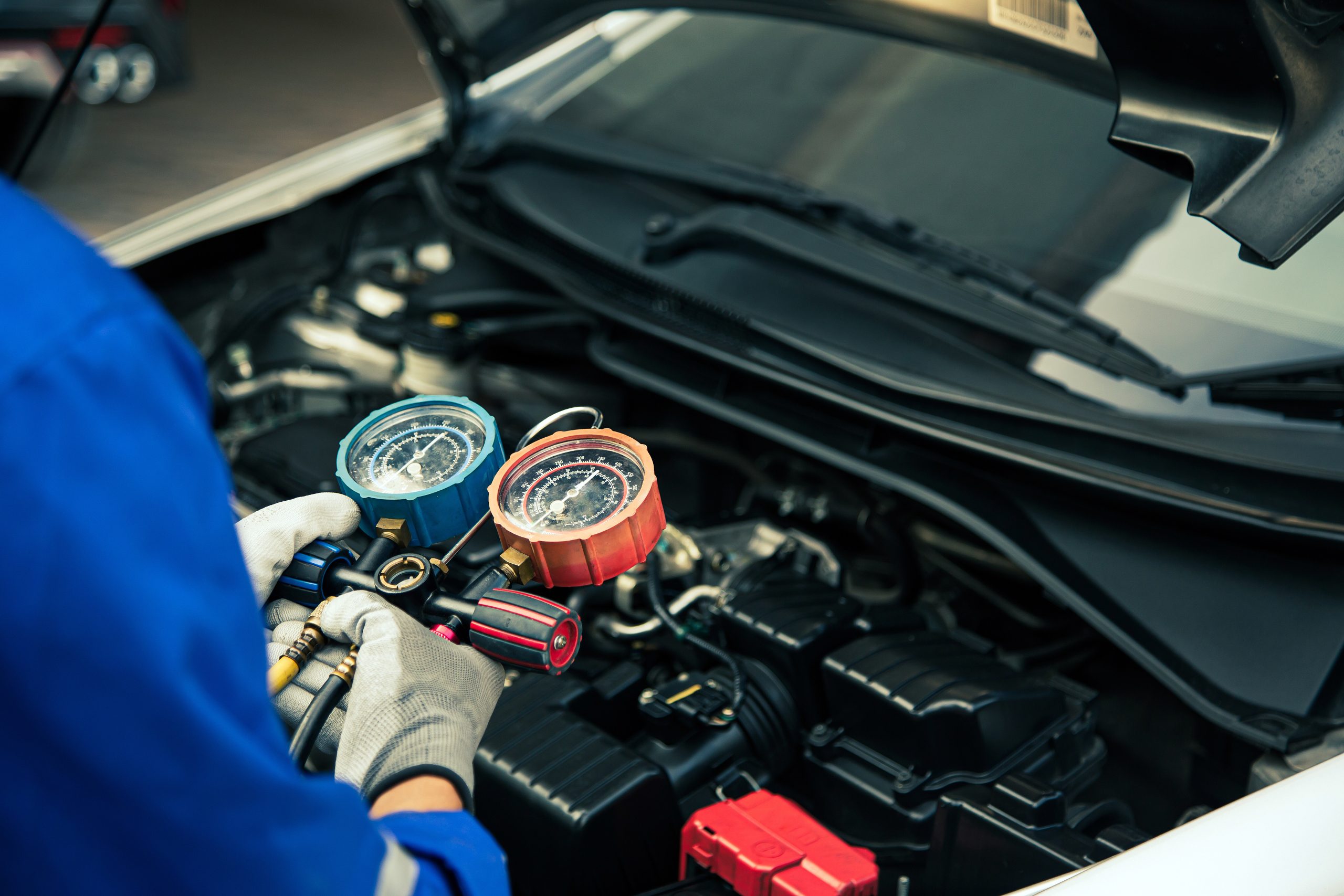 Close up hand of auto mechanic using measuring manifold gauge check the refrigerant and filling car air conditioner for fix and checking for repair service support maintenance and car insurance. Auto Heating Repair Katy TX