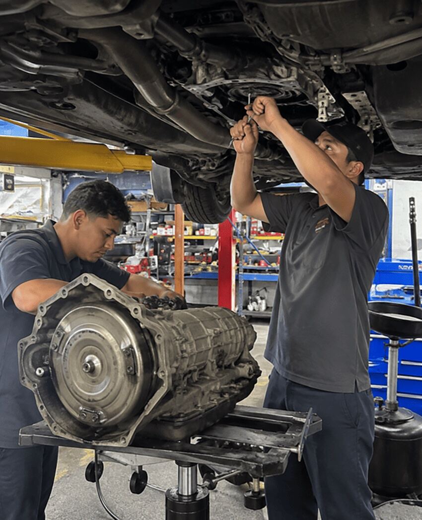 Technicians removing a transmission at Northwest Express Auto Care, Katy TX